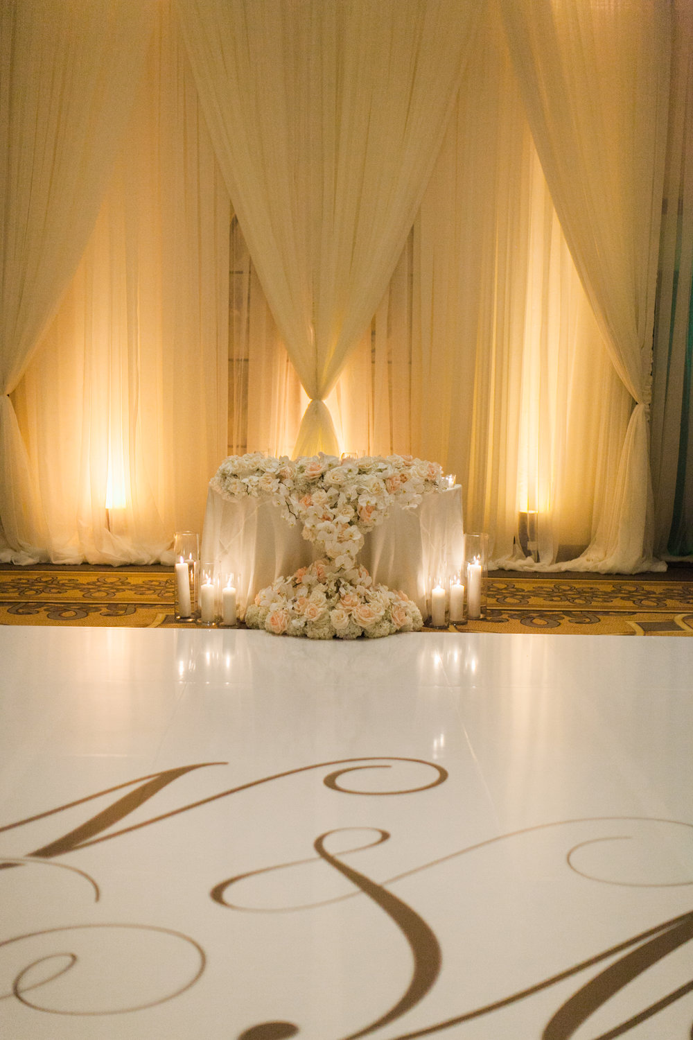Custom dance floor with the bride and groom's initials mixed with extravagant draping