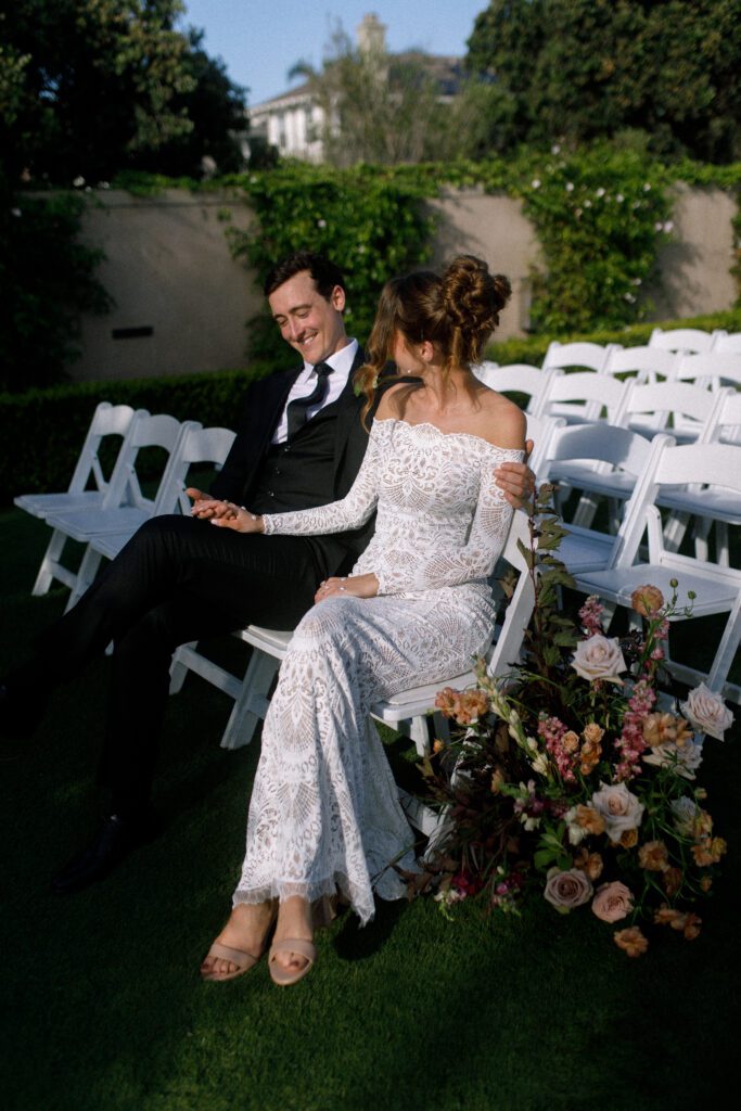 image displaying the bride and groom sitting next to each other and smiling at each other. Their wedding was a moody, romantic wedding at cape rey carlsbad in san diego