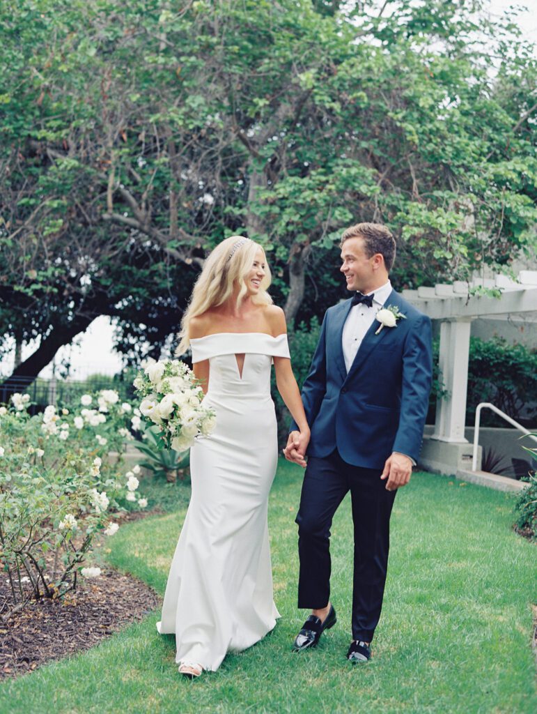 bride and groom are smiling at each other while walking and holding hands