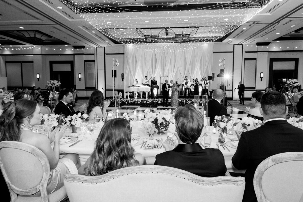 bride and groom at a wedding are watching a live band inside a ballroom