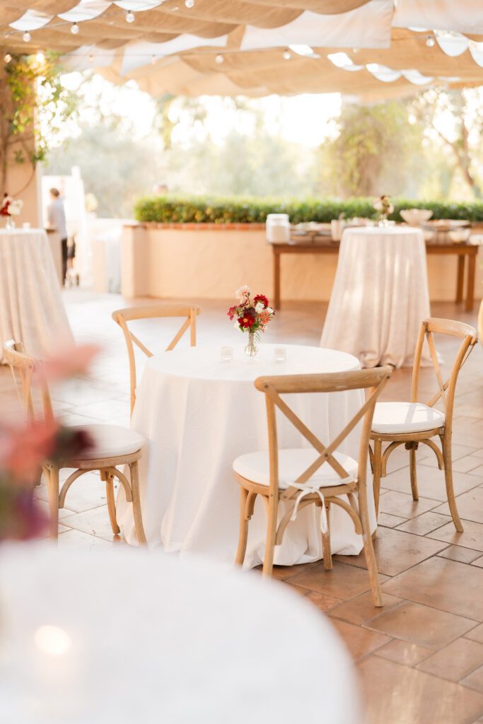 a wedding cocktail hour set up and decor at rancho bernardo inn. the decor is white with pinks, reds and greens with light wood accents
