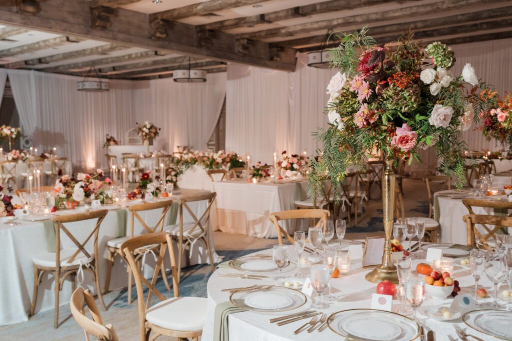  wedding reception dinner is set up in a ballroom at rancho bernardo inn. the decor is white, pinks, greens, reds with gold accents and light wood