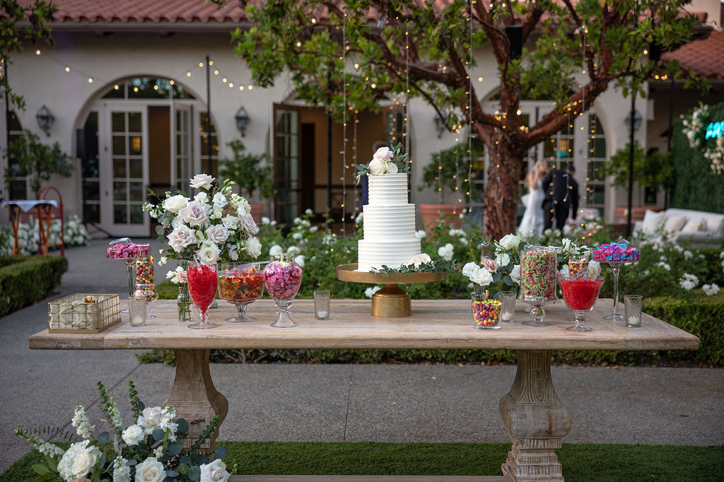a dessert table at a wedding holds a white wedding cake. the wedding is at rancho bernardo inn and coordinated by sweet blossom wedding planners