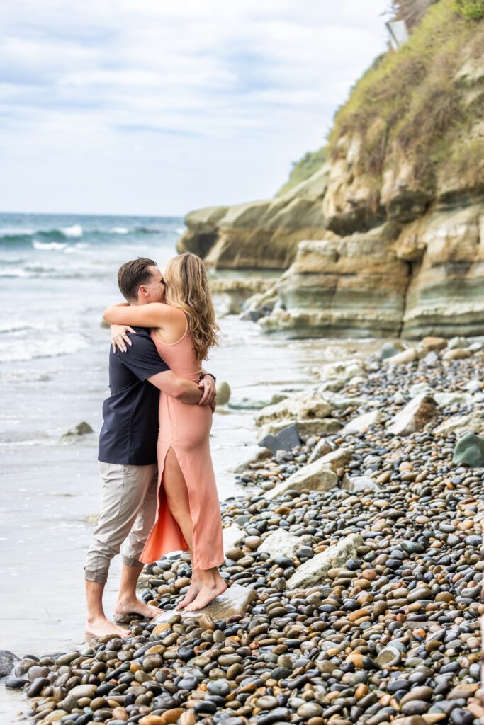 Newly engaged couple hugging at the beach and demonstrating our engagement photo tips and styling advice