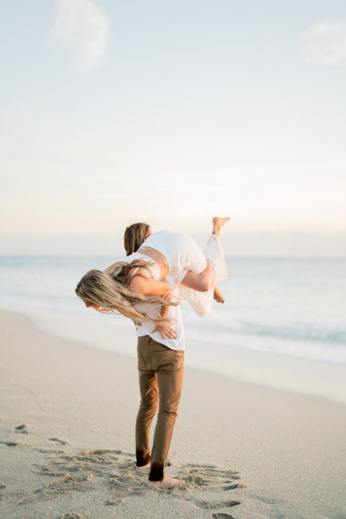 Newly engaged couple at the beach being playful and demonstrating our engagement photo tips and styling advice