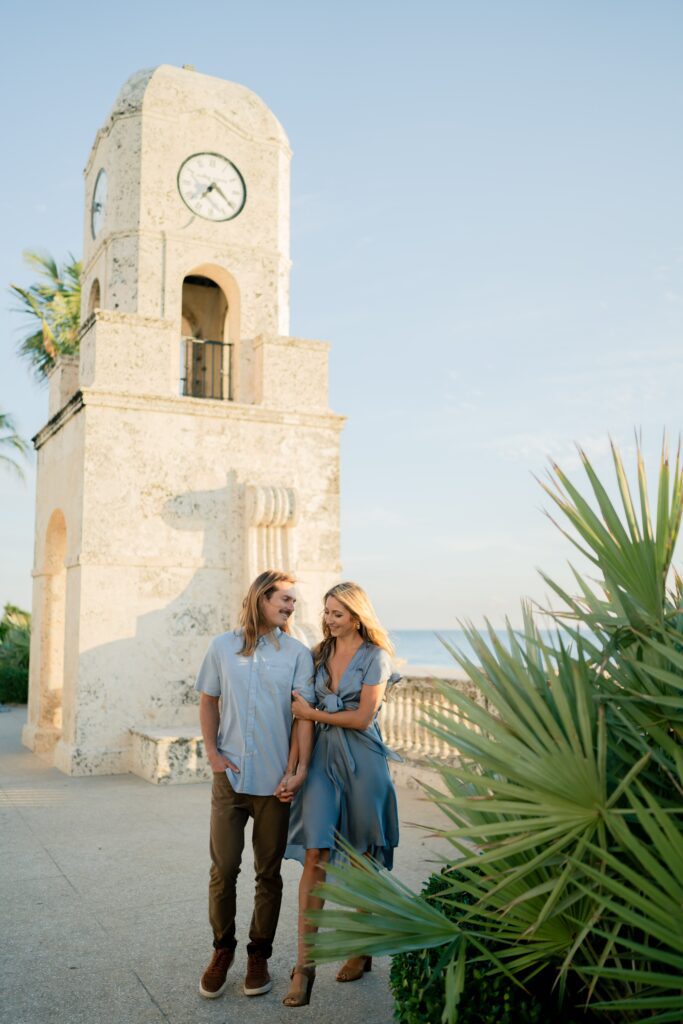 Newly engaged couple at the beach holding hands and walking together and demonstrating our engagement photo tips and styling advice