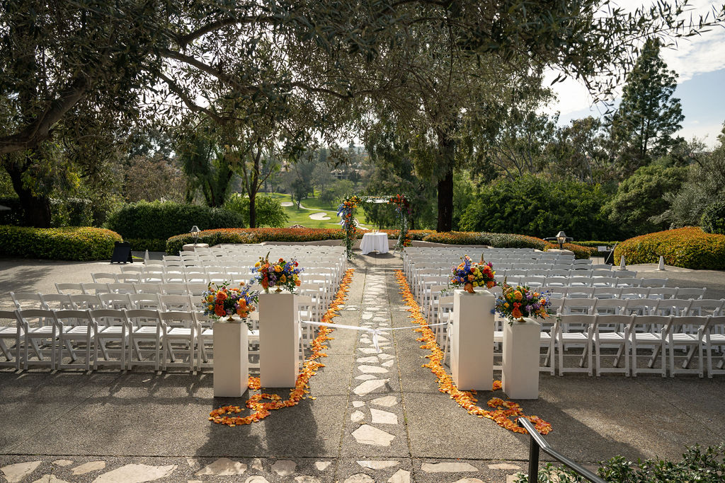 a wedding reception is taking place outdoors on a courtyard overlooking a golf course. the florals are bright and colorful
